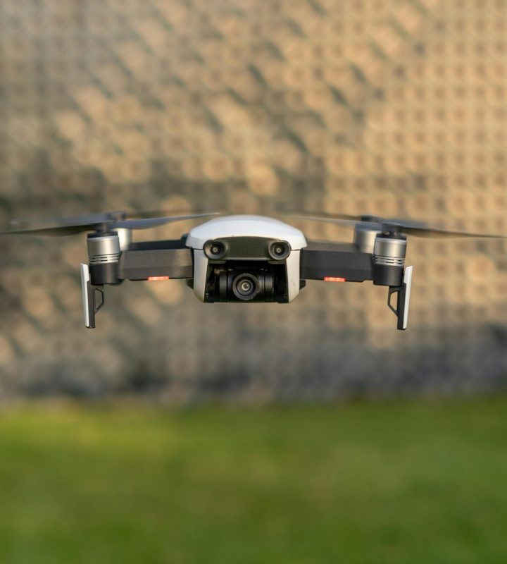 Drone in mid-flight against blurred outdoor background, showcasing technology.